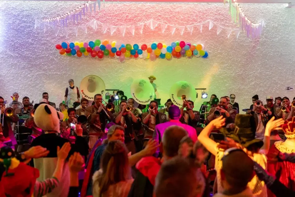 Guggenmusik spielt vor tanzenden Gaesten an der Rhyboot-Fasnachtsfeier mit bunten Ballons