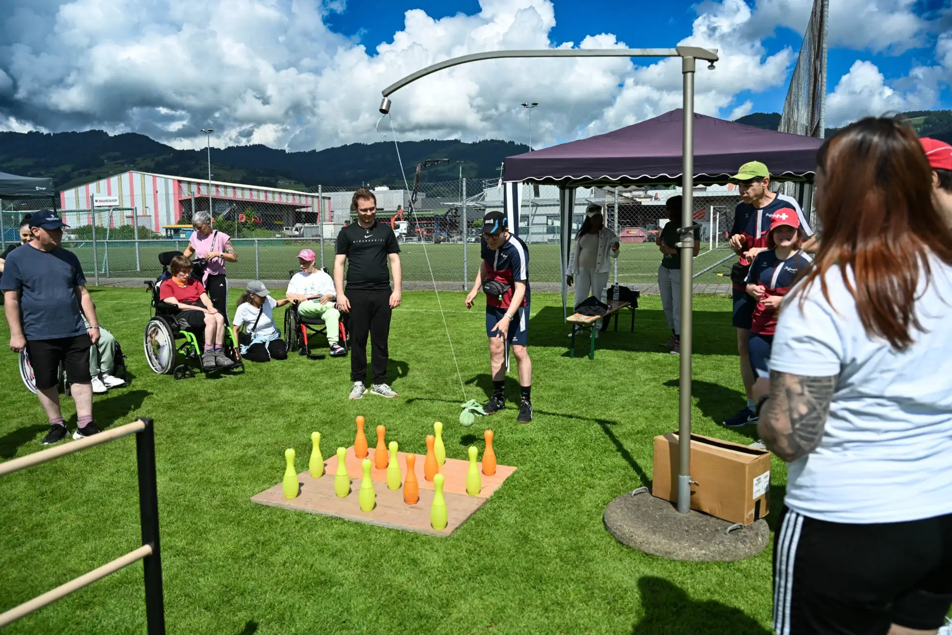 Teilnehmende mit und ohne Rollstuhl beim Kegelspiel an einem Rhyboot-Sportfest im Freien