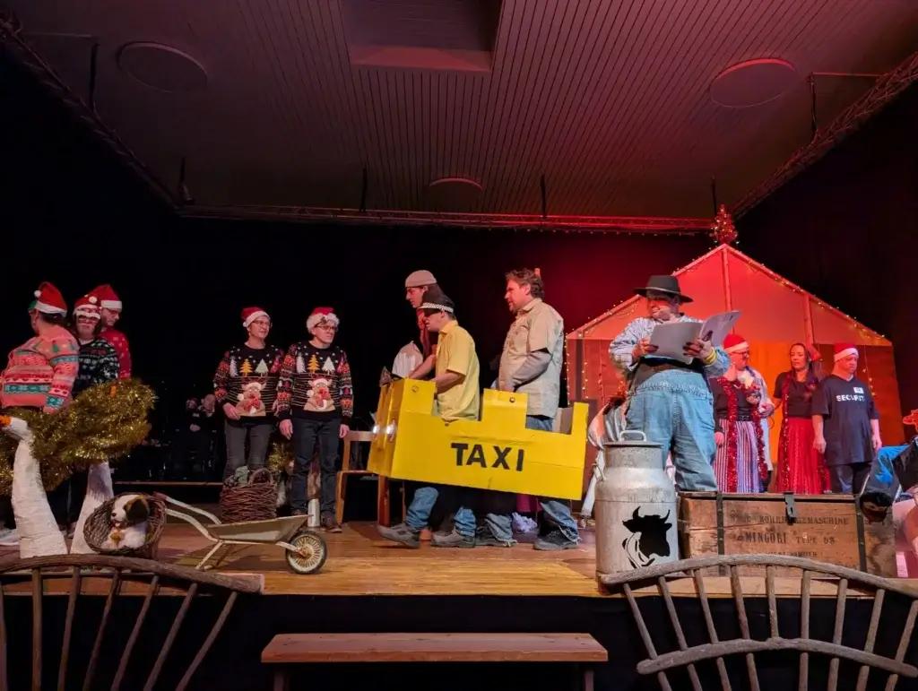 Weihnachts-Theaterszene mit Taxi-Requisite und verkleideten Darstellenden auf der Buehne