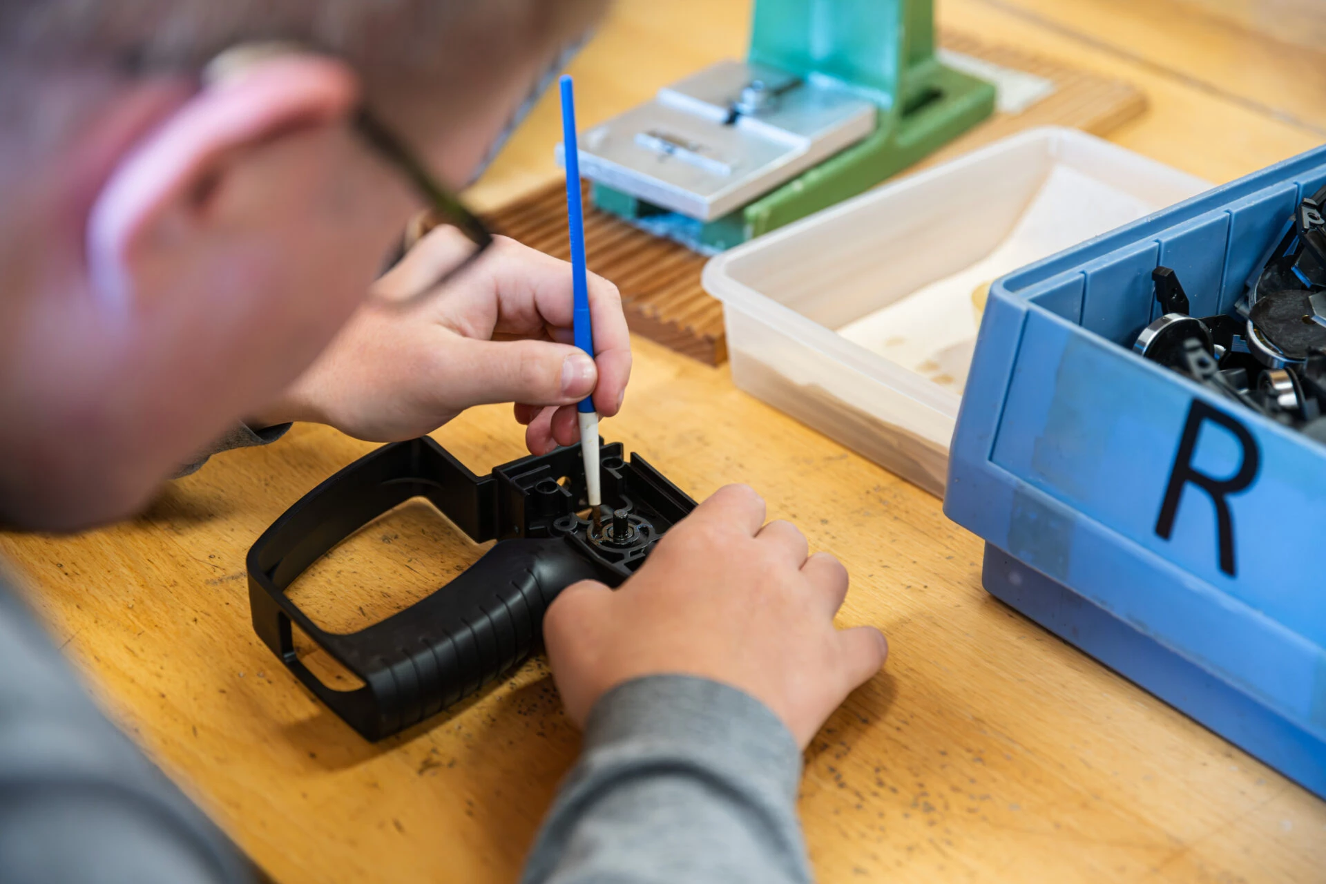 Nahaufnahme von Haenden bei feiner Montagearbeit an einem technischen Bauteil in der Produktion