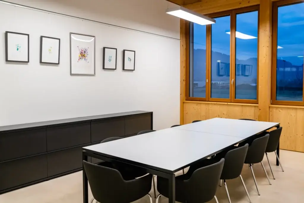 Elegantes Sitzungszimmer A1 mit Konferenztisch, gerahmten Kunstwerken und Abendstimmung