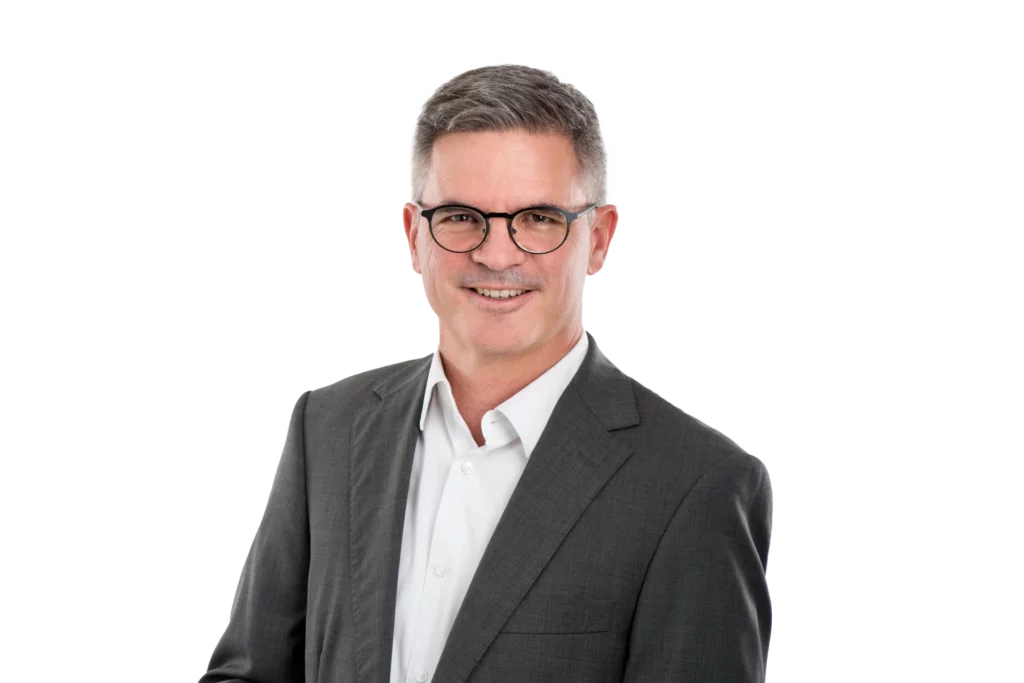 Portraetfoto von Patrick Benz im grauen Anzug mit Brille
