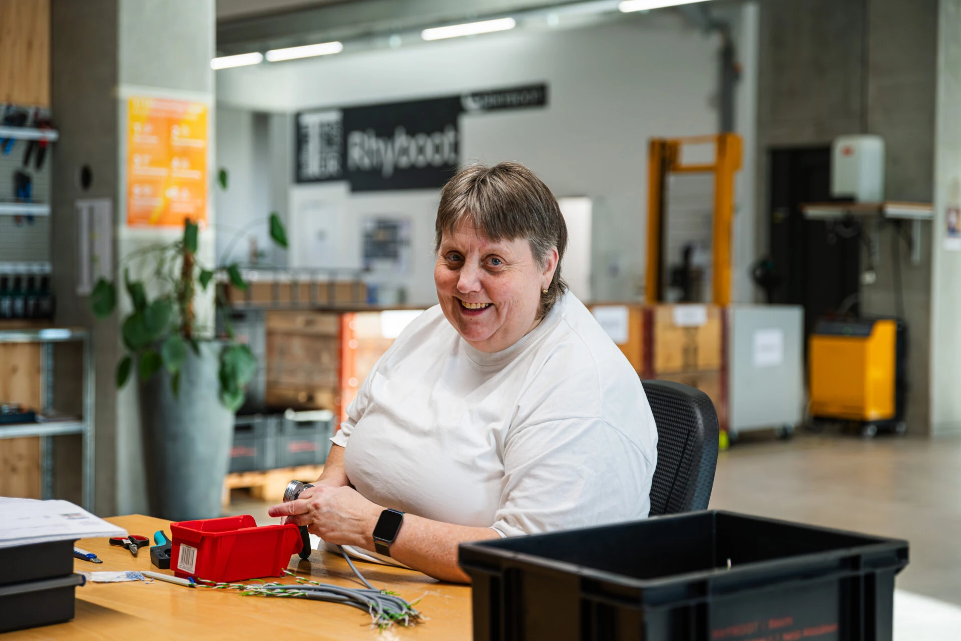 Lachende Frau bei Montagearbeiten an ihrem Arbeitsplatz in der Werkstatt von Rhyboot