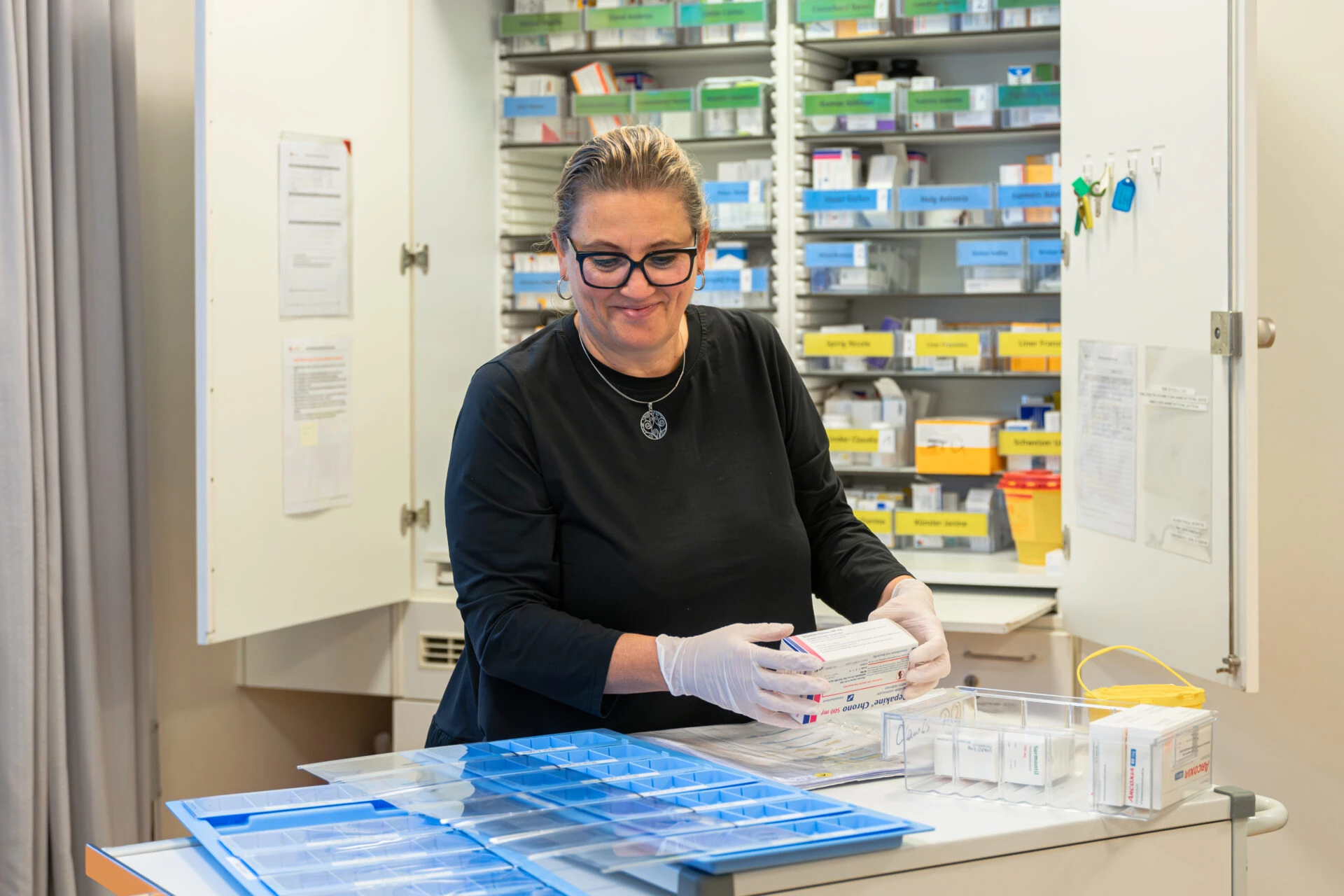 Mitarbeiterin sortiert Medikamente in Dosiersysteme im Medikamentenraum von Rhyboot