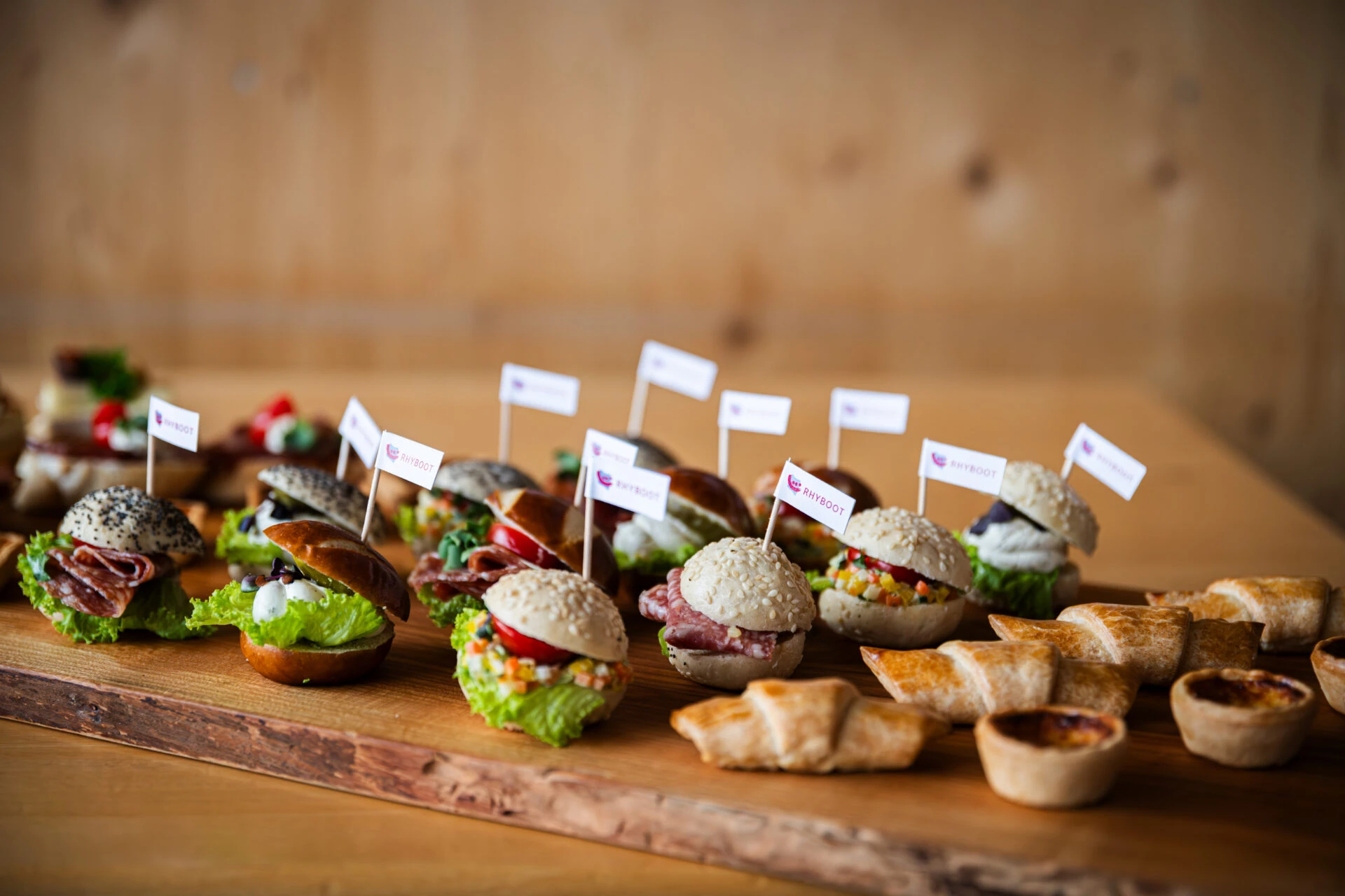 Catering-Platte mit liebevoll garnierten Mini-Burgern und Tartelettes mit Rhyboot-Faehnchen