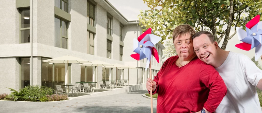 Florian und Nicole mit Windraedern vor der gruenen Fassade des Wohnhauses Wyden