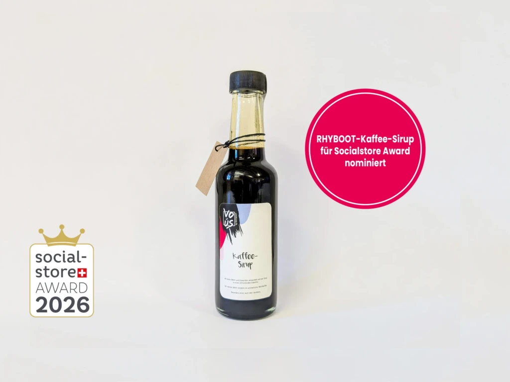 Produktbild des RHYBOOT-Kaffee-Sirups vor grauem Hintergrund mit dem Logo des Socialstore Awards sowie Störer-Kreis mit Text "RHYBOOT-Kaffee-Sirup für Socialstore Award nominiert"